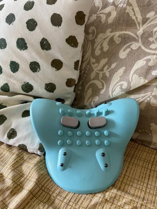 Blue back stretcher with knobs on patterned bedding.