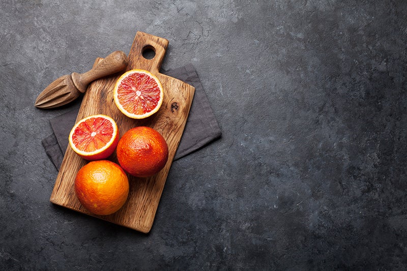 Moro blood oranges on a wooden cutting board with a citrus juicer
