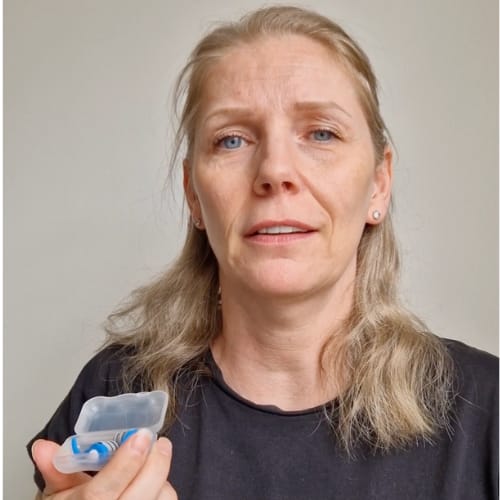 Person holding a small open container with blue and white object inside.